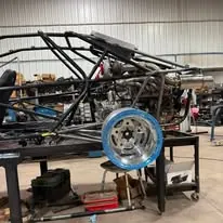 The sand car's tube chassis on the fabrication table during the rebuild, beadlock wheel test-fitted