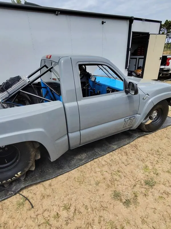 Top Gun in the pits, rear three-quarter view showing the blue interior, cage and TT door decal