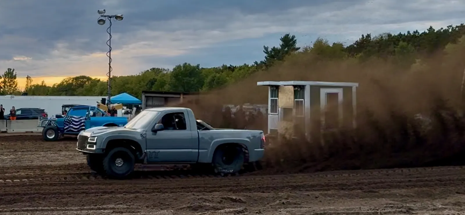Top Gun launching past the timing tower at sunset, huge dirt roost behind it