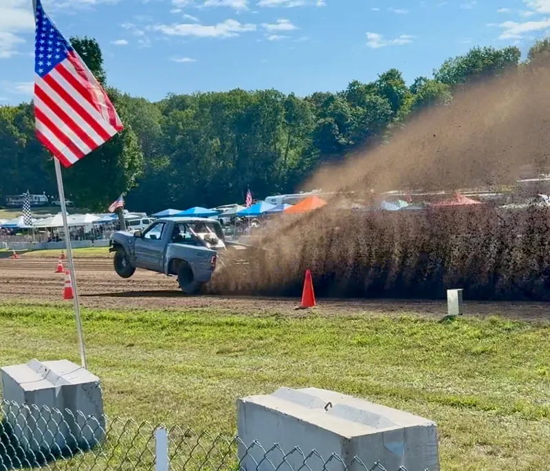 Top Gun launching with the front wheel up, dirt roost, American flag in the foreground